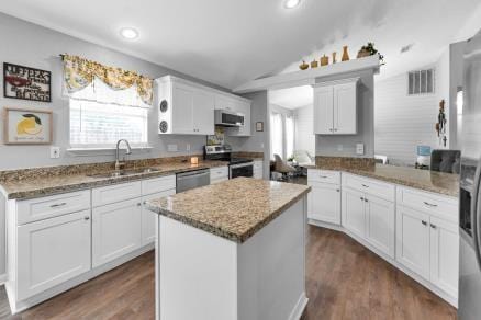 kitchen featuring stainless steel appliances, sink, white cabinetry, lofted ceiling, and a kitchen island