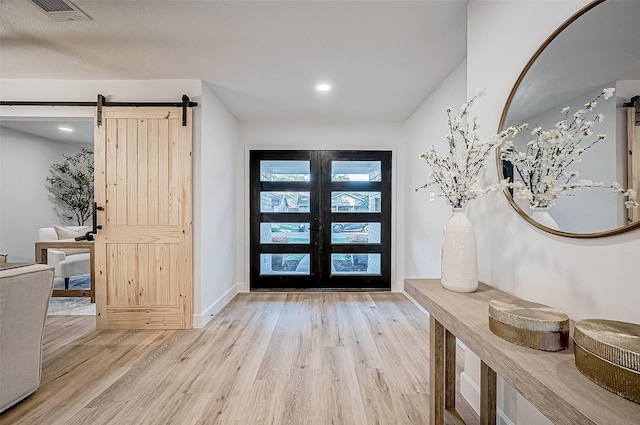 entrance foyer featuring french doors, a barn door, and light hardwood / wood-style floors