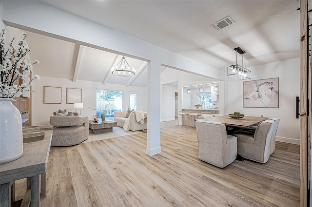 dining space featuring lofted ceiling, a notable chandelier, and light hardwood / wood-style flooring