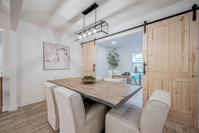 dining space featuring light wood-type flooring and a barn door