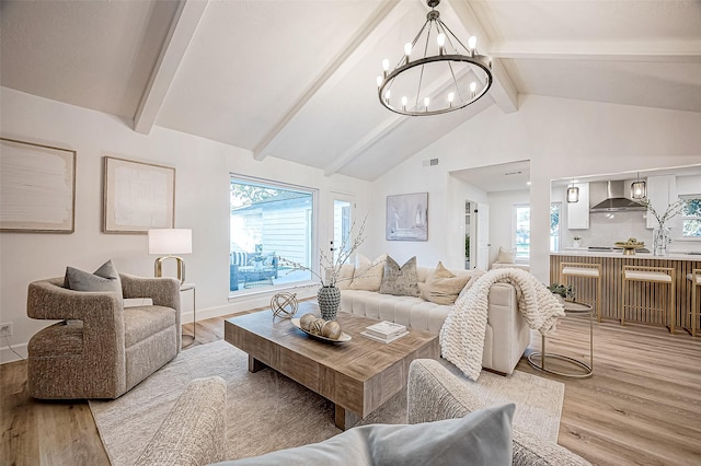 living room with light hardwood / wood-style floors, vaulted ceiling with beams, and a chandelier