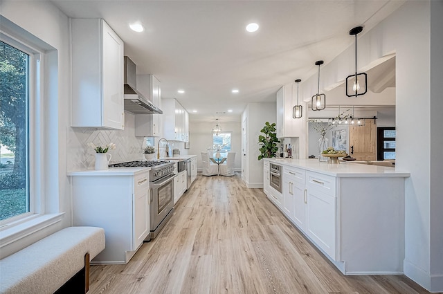 kitchen with white cabinets, wall chimney exhaust hood, and high end stainless steel range oven