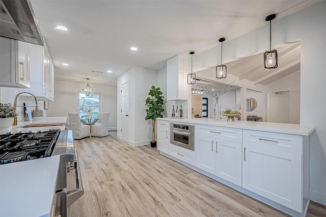 kitchen with vaulted ceiling, pendant lighting, stainless steel appliances, light wood-type flooring, and white cabinetry