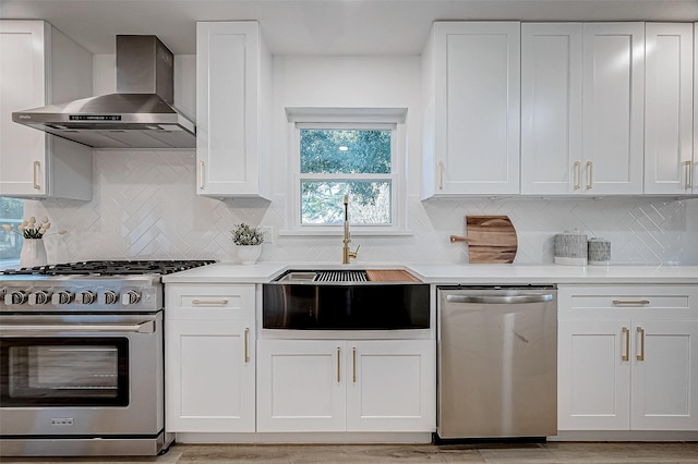 kitchen featuring white cabinets, stainless steel appliances, wall chimney range hood, and backsplash