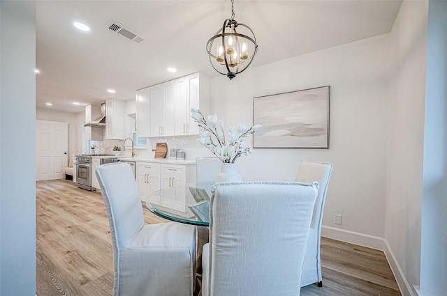 dining area with light hardwood / wood-style flooring, a chandelier, and sink