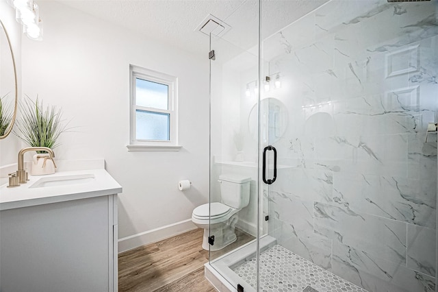 bathroom featuring hardwood / wood-style floors, toilet, walk in shower, vanity, and a textured ceiling