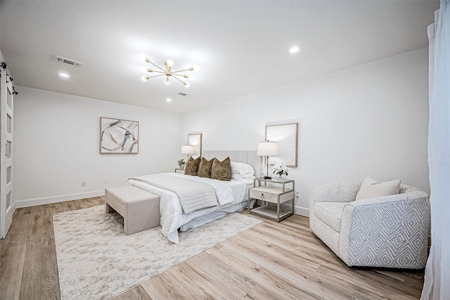 bedroom featuring an inviting chandelier and light hardwood / wood-style floors