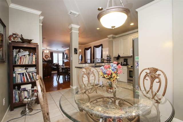 dining space featuring sink, ornate columns, light tile patterned floors, ornamental molding, and ceiling fan