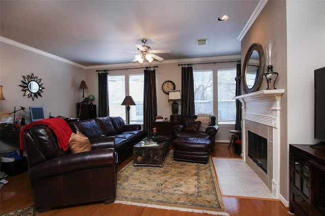 living room with a fireplace, light hardwood / wood-style flooring, ornamental molding, and ceiling fan