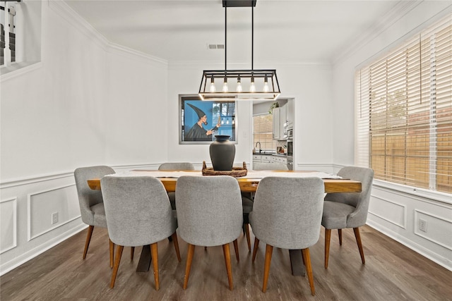 dining space with sink, ornamental molding, and dark hardwood / wood-style floors