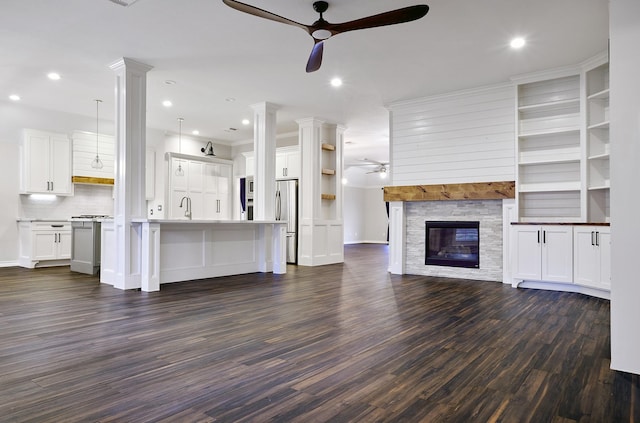 unfurnished living room with ceiling fan, dark wood-type flooring, sink, and a fireplace