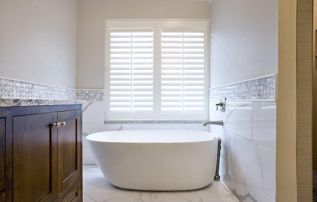 bathroom featuring a washtub, vanity, and tile walls