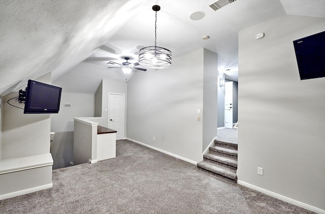 interior space featuring lofted ceiling, a textured ceiling, dark colored carpet, and ceiling fan