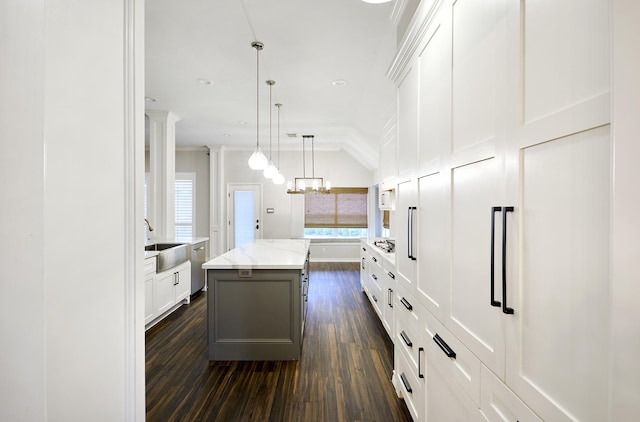 kitchen featuring a center island, dark hardwood / wood-style flooring, pendant lighting, light stone counters, and white cabinetry