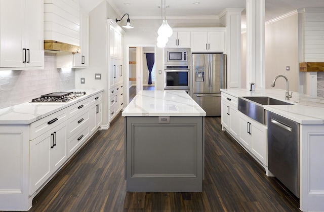 kitchen featuring pendant lighting, stainless steel appliances, a kitchen island with sink, white cabinets, and sink