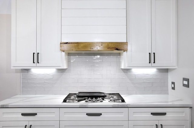 kitchen featuring white cabinetry, stainless steel gas cooktop, backsplash, and light stone countertops