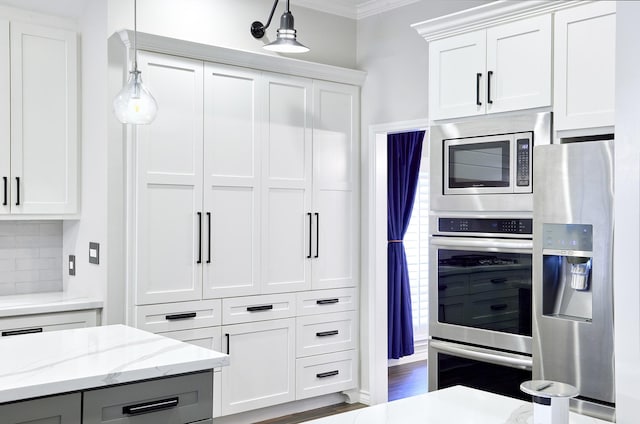 kitchen with stainless steel appliances, white cabinets, and hanging light fixtures