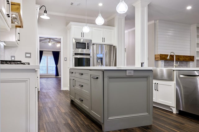 kitchen featuring decorative light fixtures, decorative backsplash, a kitchen island, white cabinets, and appliances with stainless steel finishes