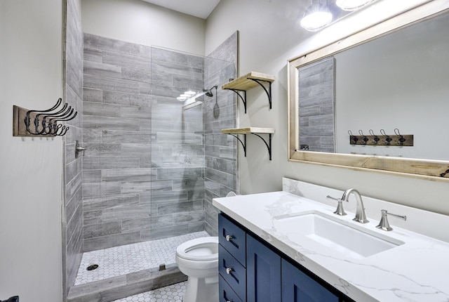 bathroom with toilet, tiled shower, and vanity