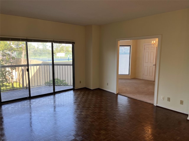 empty room featuring dark parquet floors and a chandelier