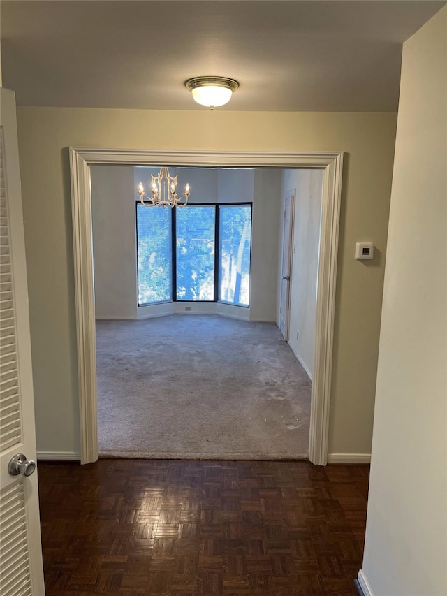 corridor featuring dark parquet floors and an inviting chandelier