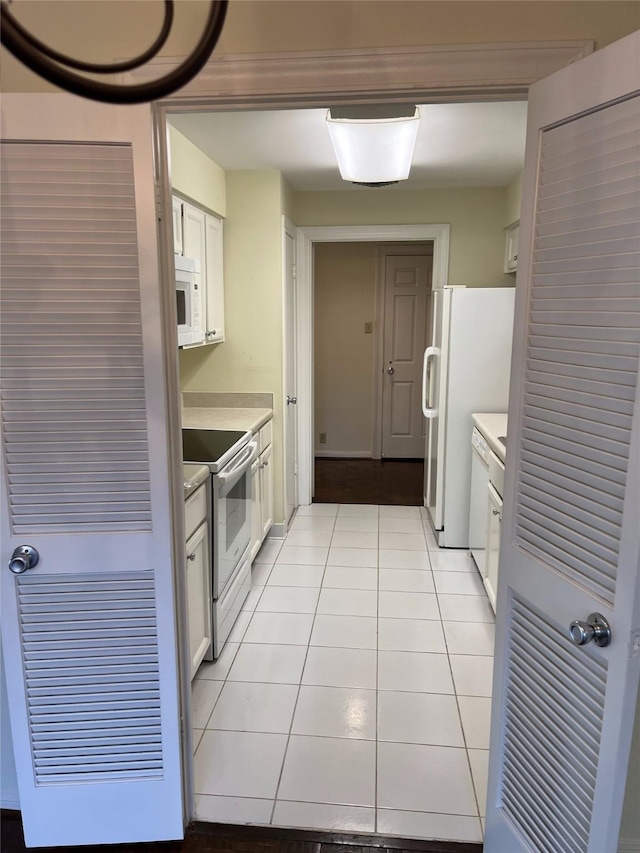 kitchen with light tile patterned floors, white cabinets, and white appliances