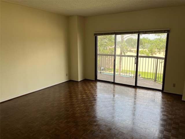 spare room featuring dark parquet floors and a textured ceiling