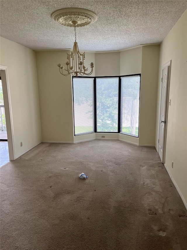 carpeted spare room featuring a chandelier and a textured ceiling