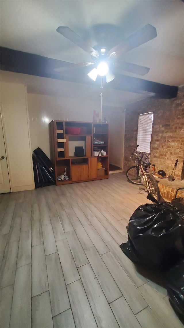 interior space with ceiling fan, brick wall, and light wood-type flooring