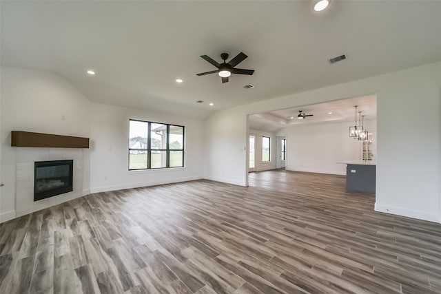 unfurnished living room with dark hardwood / wood-style flooring, lofted ceiling, ceiling fan with notable chandelier, and a fireplace