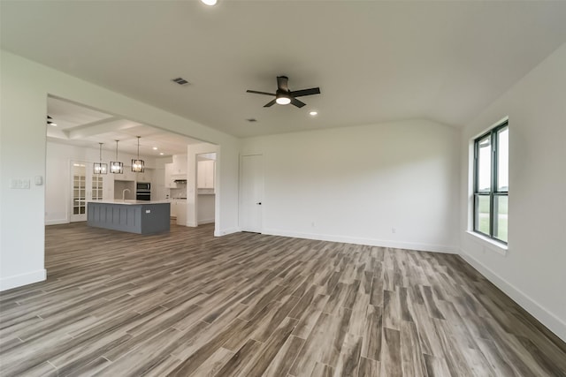 unfurnished living room featuring ceiling fan with notable chandelier, hardwood / wood-style floors, and sink