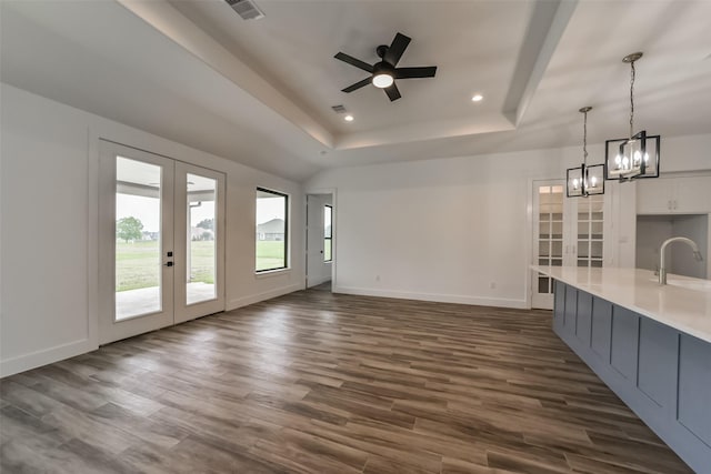 unfurnished living room featuring sink, dark wood-type flooring, french doors, and a raised ceiling