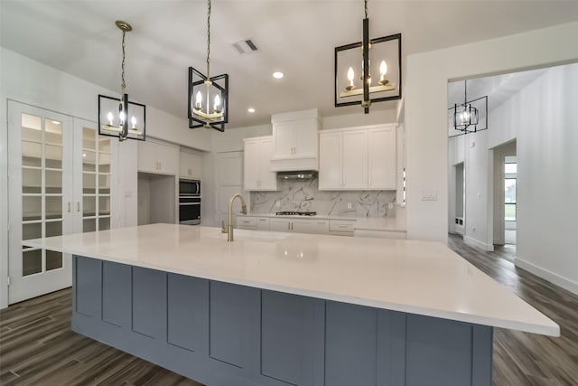 kitchen featuring sink, decorative light fixtures, white cabinets, a spacious island, and appliances with stainless steel finishes