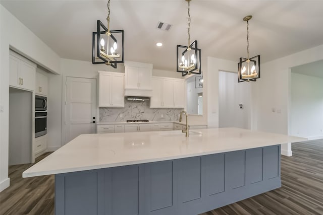 kitchen featuring white cabinets, appliances with stainless steel finishes, a large island, and hanging light fixtures