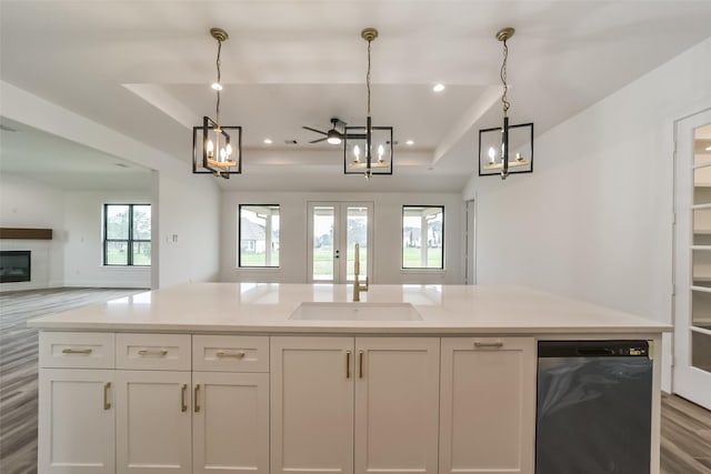 kitchen featuring ceiling fan, pendant lighting, a tray ceiling, sink, and white cabinetry