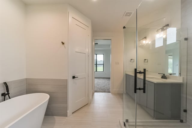 bathroom featuring shower with separate bathtub, vanity, tile walls, and tile patterned flooring