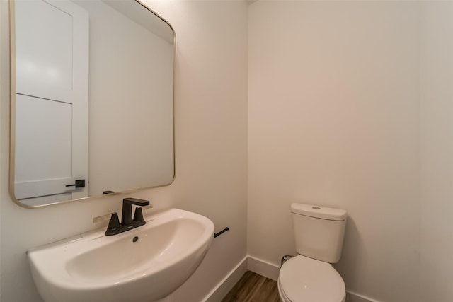 bathroom featuring toilet, wood-type flooring, and sink