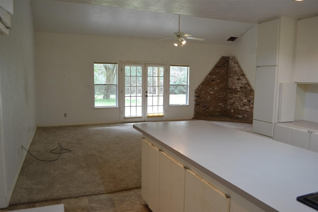 interior space with ceiling fan, light colored carpet, white cabinetry, and french doors