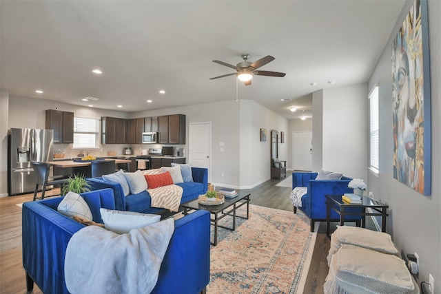 living room featuring light hardwood / wood-style floors, ceiling fan, and plenty of natural light