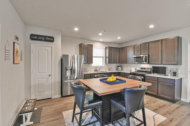 kitchen featuring light hardwood / wood-style floors, stainless steel appliances, and dark brown cabinets