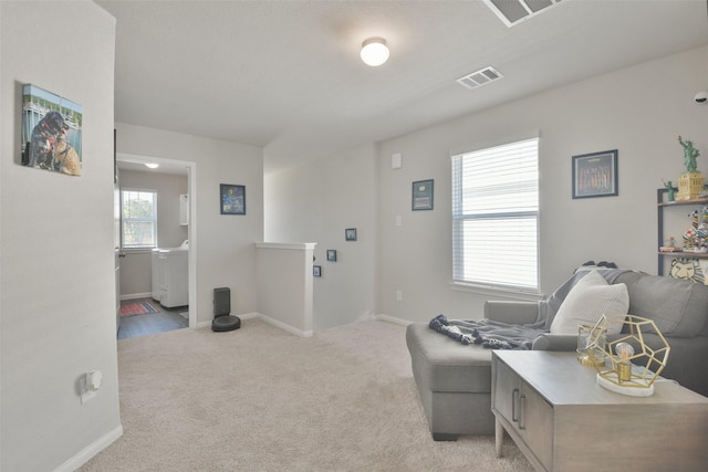 living area featuring washer / dryer and light carpet