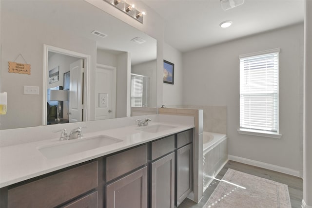 bathroom featuring plenty of natural light, hardwood / wood-style flooring, a bath, and vanity