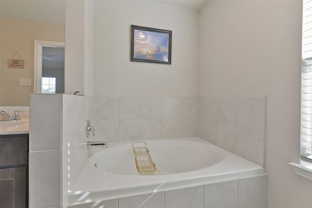 bathroom featuring a relaxing tiled tub and vanity