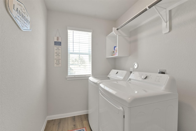 clothes washing area featuring washing machine and dryer, light hardwood / wood-style flooring, and a wealth of natural light