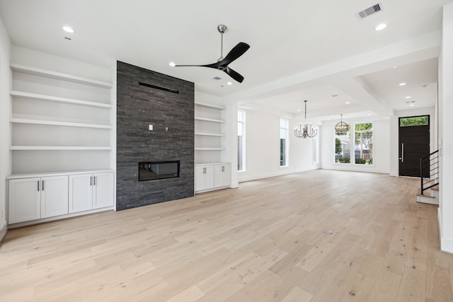 unfurnished living room featuring visible vents, a fireplace, light wood-style flooring, stairs, and ceiling fan with notable chandelier