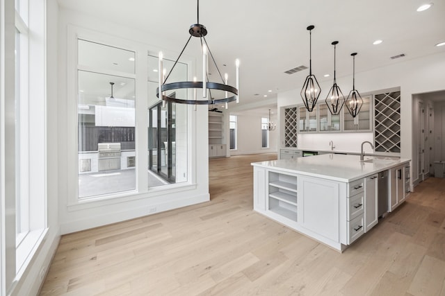 kitchen featuring a chandelier, light wood finished floors, and a sink