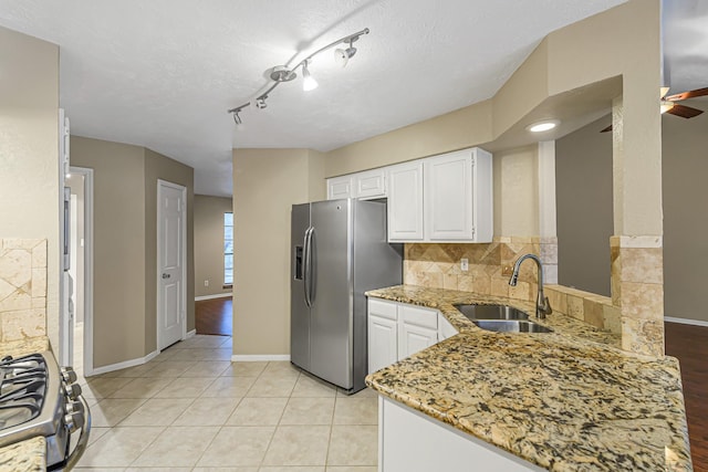 kitchen featuring white cabinets, stainless steel appliances, light stone counters, sink, and backsplash