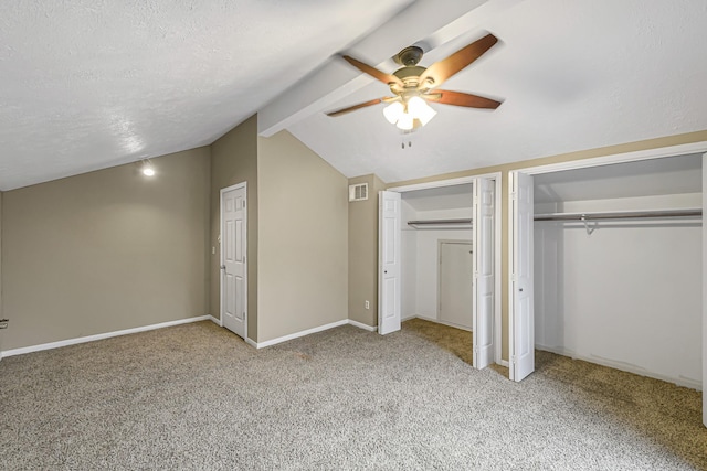 unfurnished bedroom with ceiling fan, multiple closets, carpet, and lofted ceiling with beams