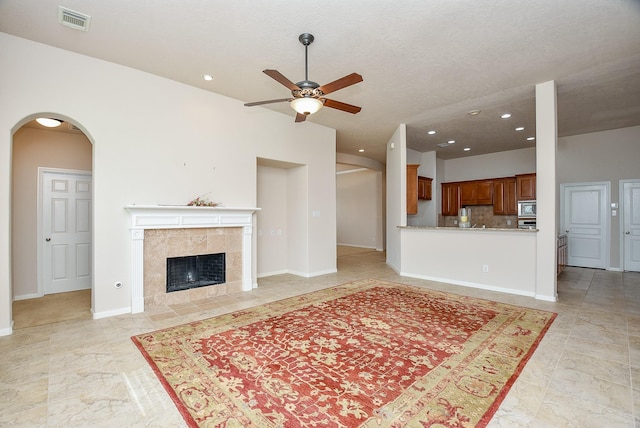 living room featuring ceiling fan and a tiled fireplace