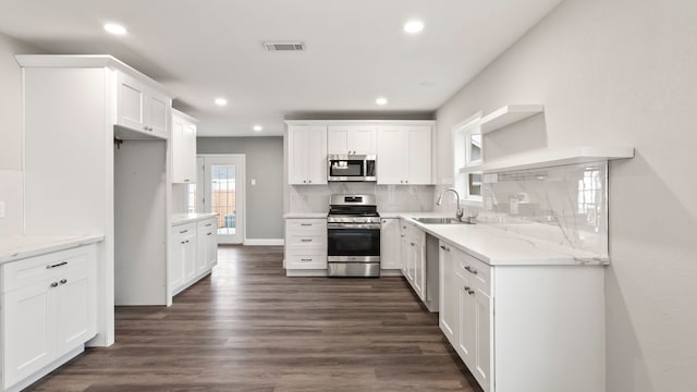 kitchen with stainless steel appliances, dark hardwood / wood-style flooring, sink, white cabinets, and tasteful backsplash